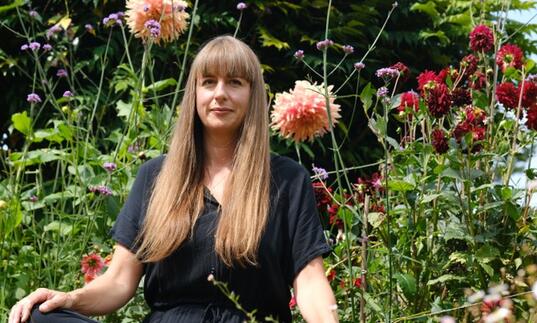 Image of Jemma Foster sat amongst plants and flowers.